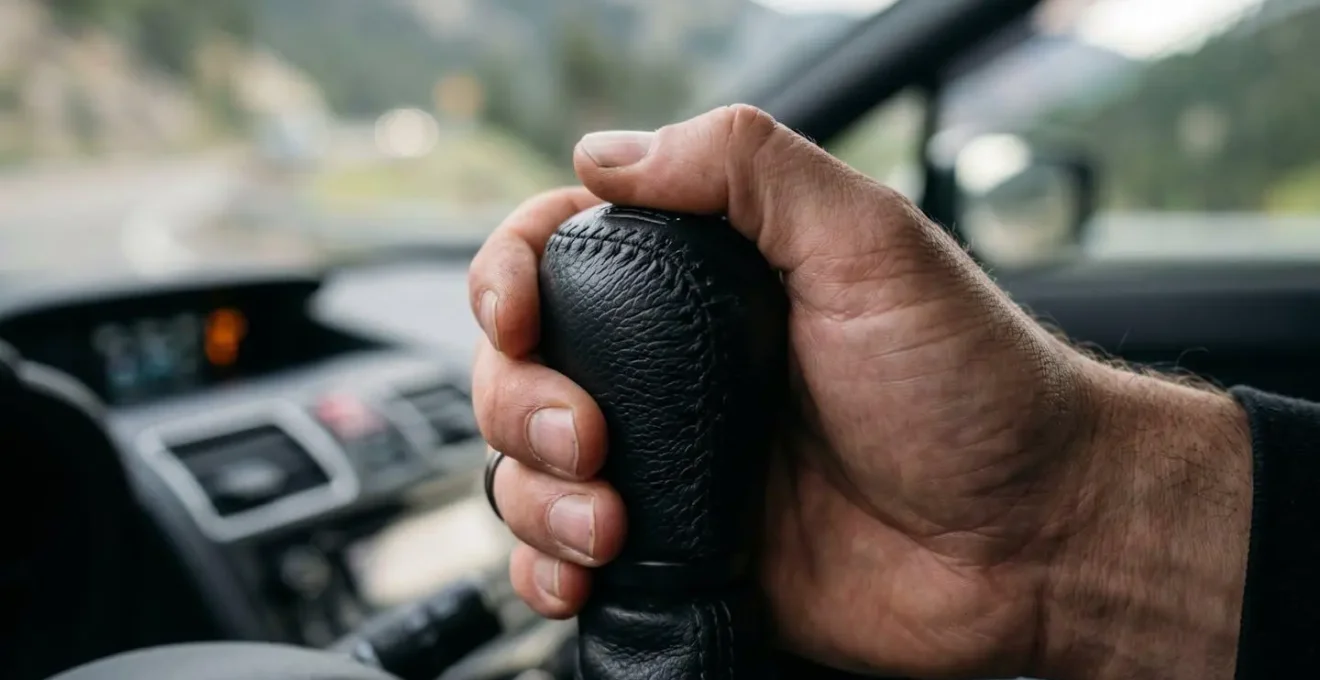 Dettaglio macro della leva del cambio di un'automobile durante una manovra di scalata marcia in discesa montana